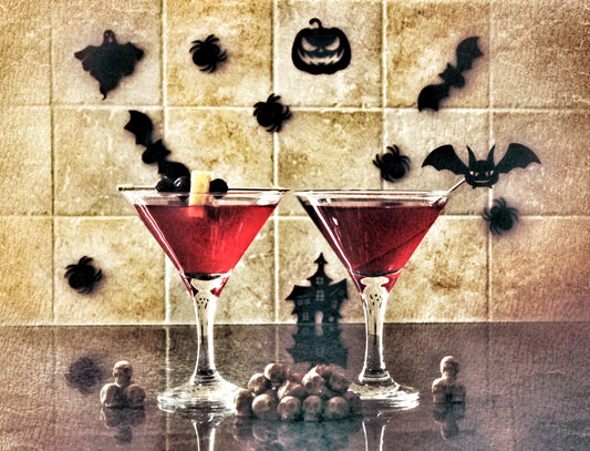 Blood Moon spiced rum cocktail made using Swan Knight Distillery golden spiced rum in 2 martini glasses and surrounded by spooky things