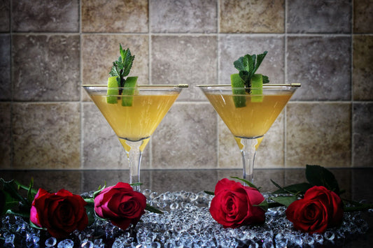 Hello Winter Nights spiced rum cocktail made with Swan Knight Distillery golden spiced rum, in 2 martini glasses and surrounded by roses