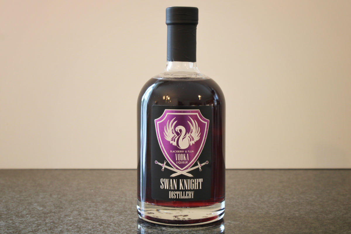 A bottle of Swan Knight Distillery Blackberry and Plum Vodka Liqueur on a dark countertop.
