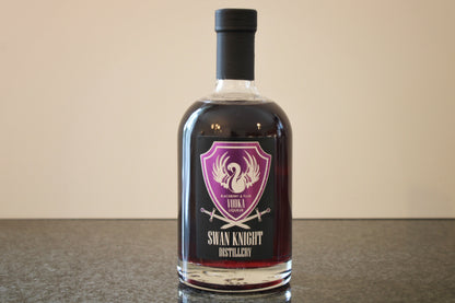 A bottle of Swan Knight Distillery Blackberry and Plum Vodka Liqueur on a dark countertop.