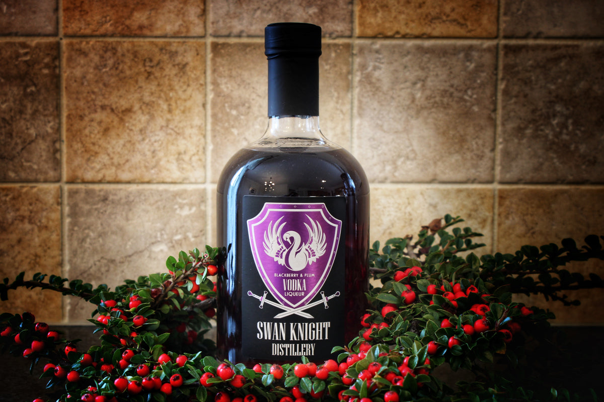 A bottle of Swan Knight Distillery Blackberry and Plum Vodka Liqueur surrounded by seasonal red berries