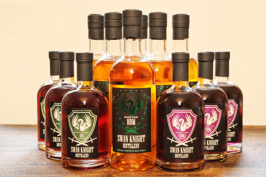 A collection of bottles from the Swan Knight Distillery range, showcasing the flagship Golden Spiced Rum, the Elderflower & Dark Berry Gin liqueur and the Blackberry & Plum Vodka liqueur.
