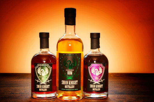 3 bottles from the Swan Knight Distillery collection, showcasing the flagship Golden Spiced Rum, the Elderflower & Dark Berry Gin liqueur and the Blackberry & Plum Vodka liqueur.